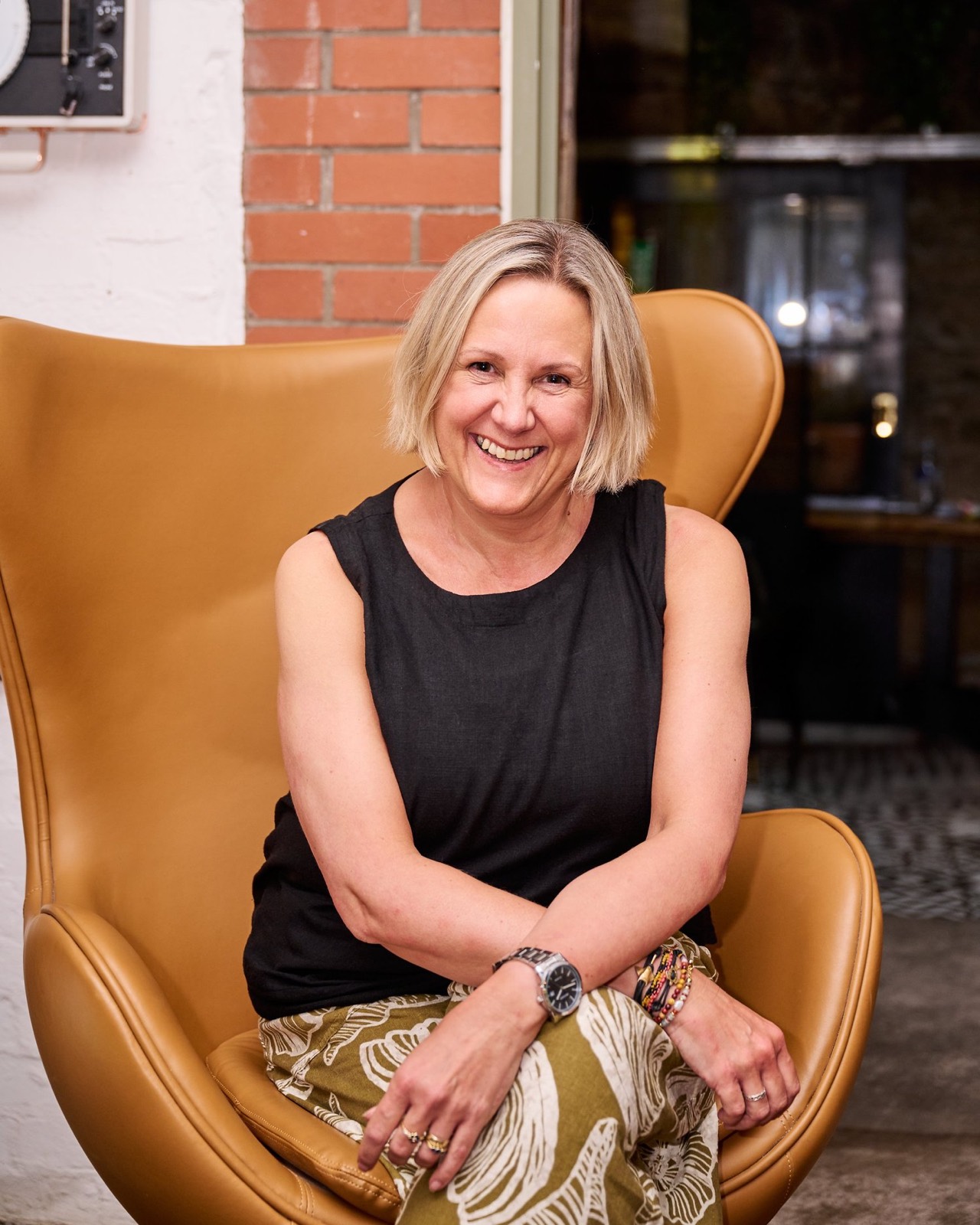 A smiling woman in a tan leather armchair