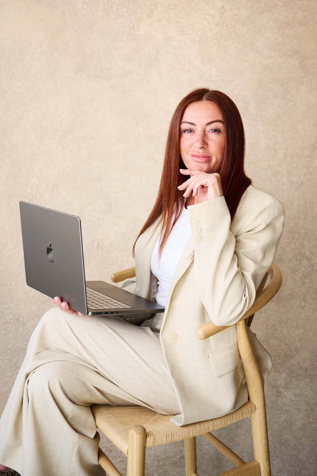 Nickie with a laptop in a cream trouser suit