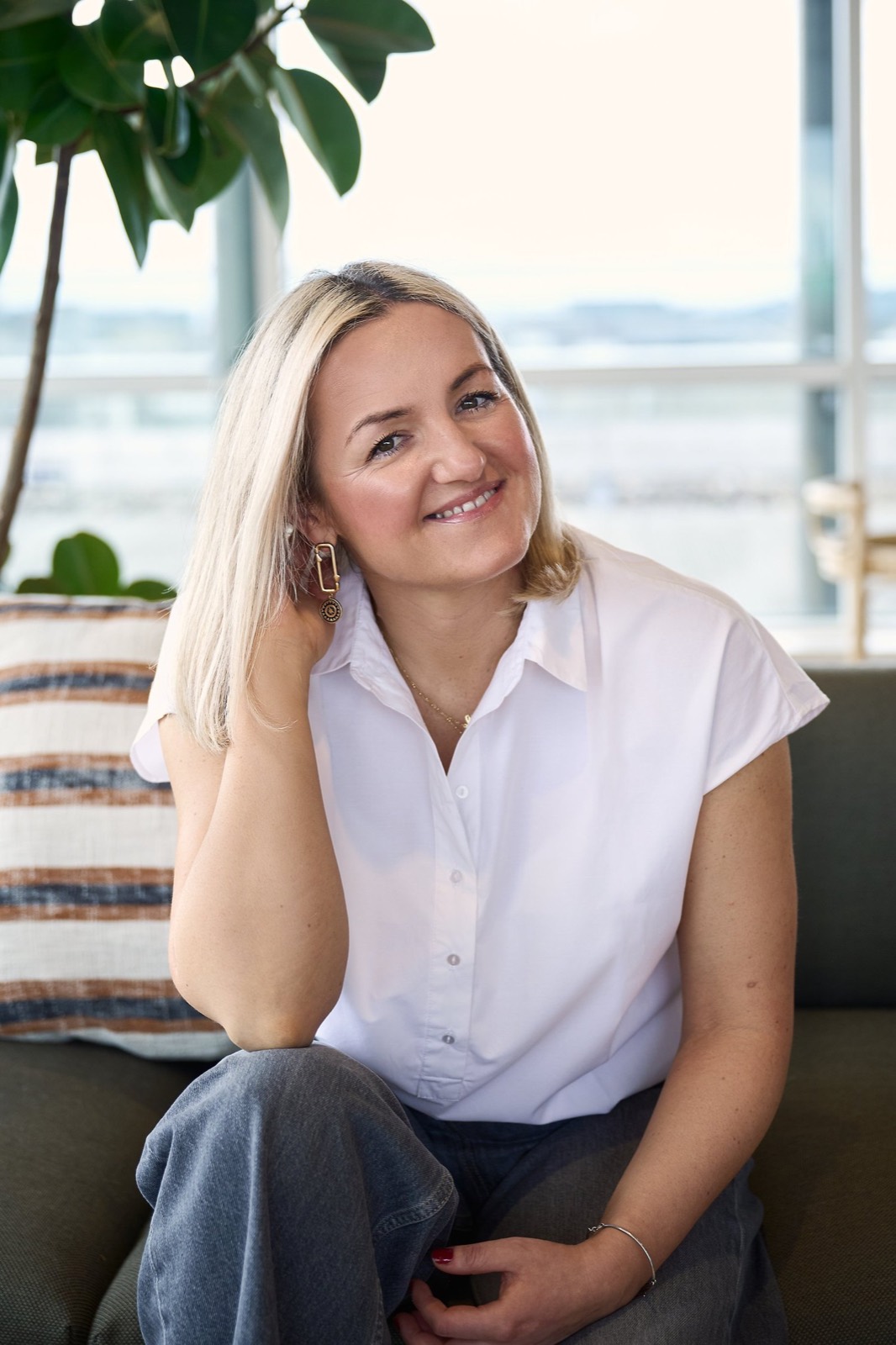 A smiling woman in a white shirt on a sofa