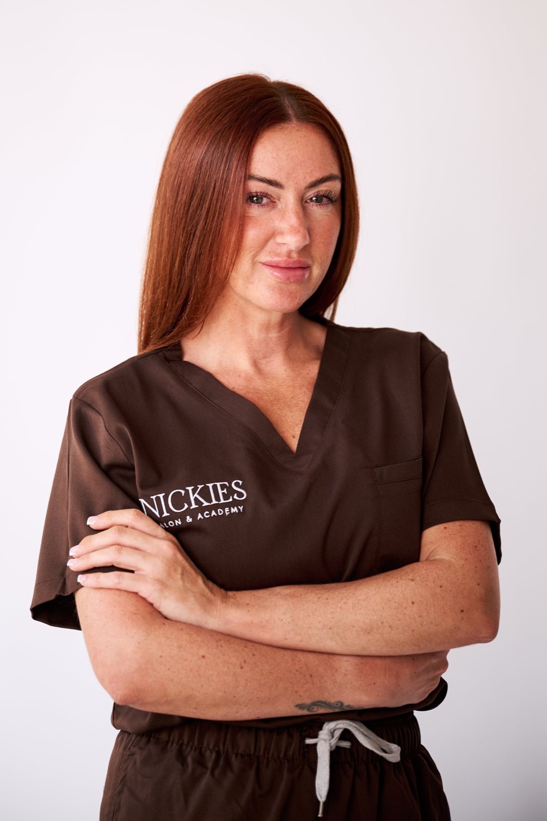 Nickie with her arms folded in her salon tunic