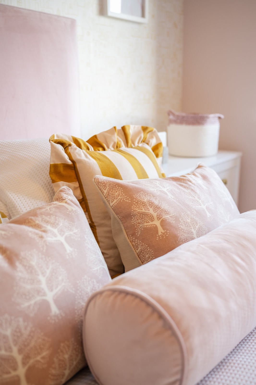 Blush and mustard cushions on a pink bed