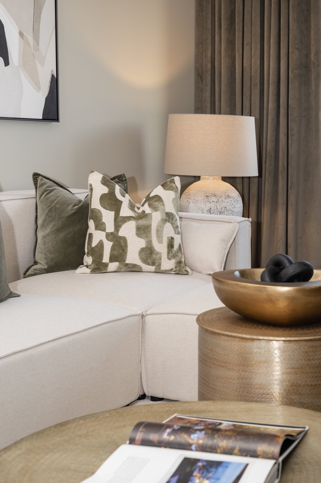 A cream sofa with patterned cushions and a brass bowl