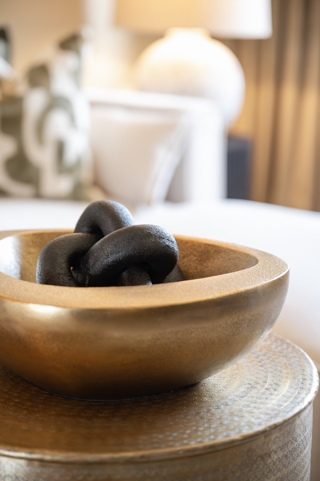 A brass bowl with dark stones on a side table