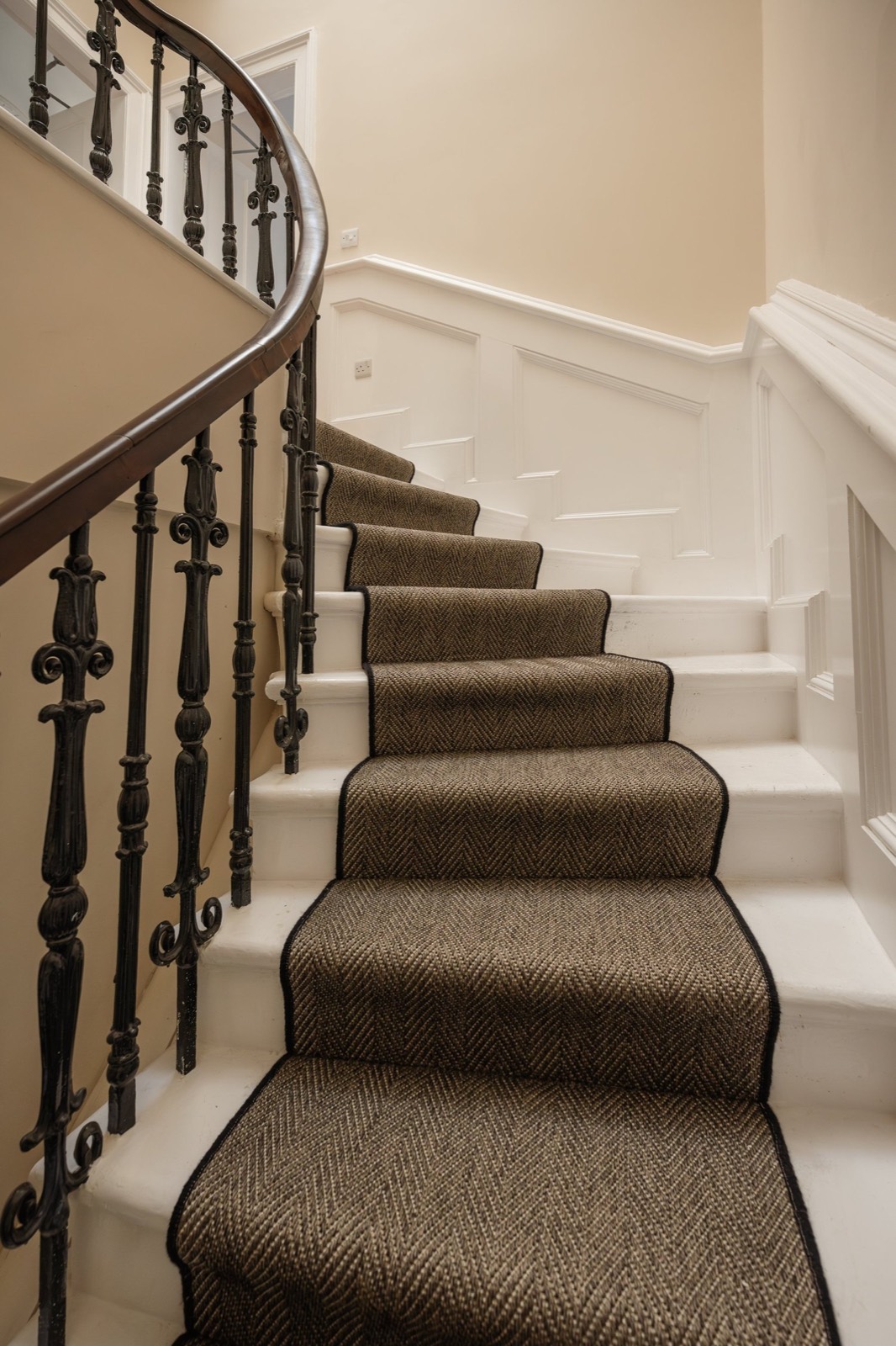 A curving staircase with a striped runner