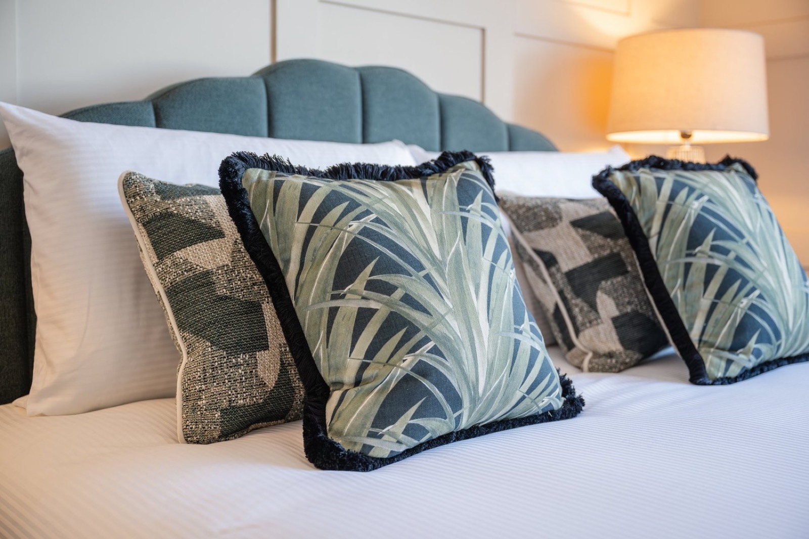 Palm-print cushions on a velvet headboard