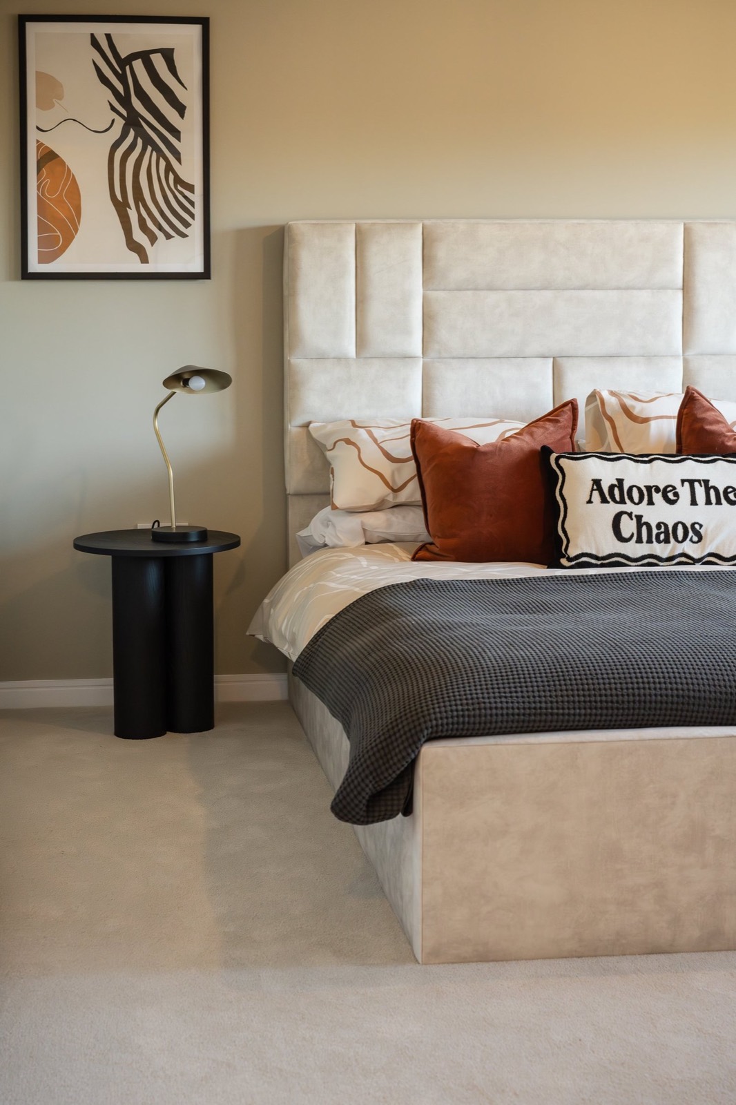 A bedroom with an abstract print and an embroidered cushion