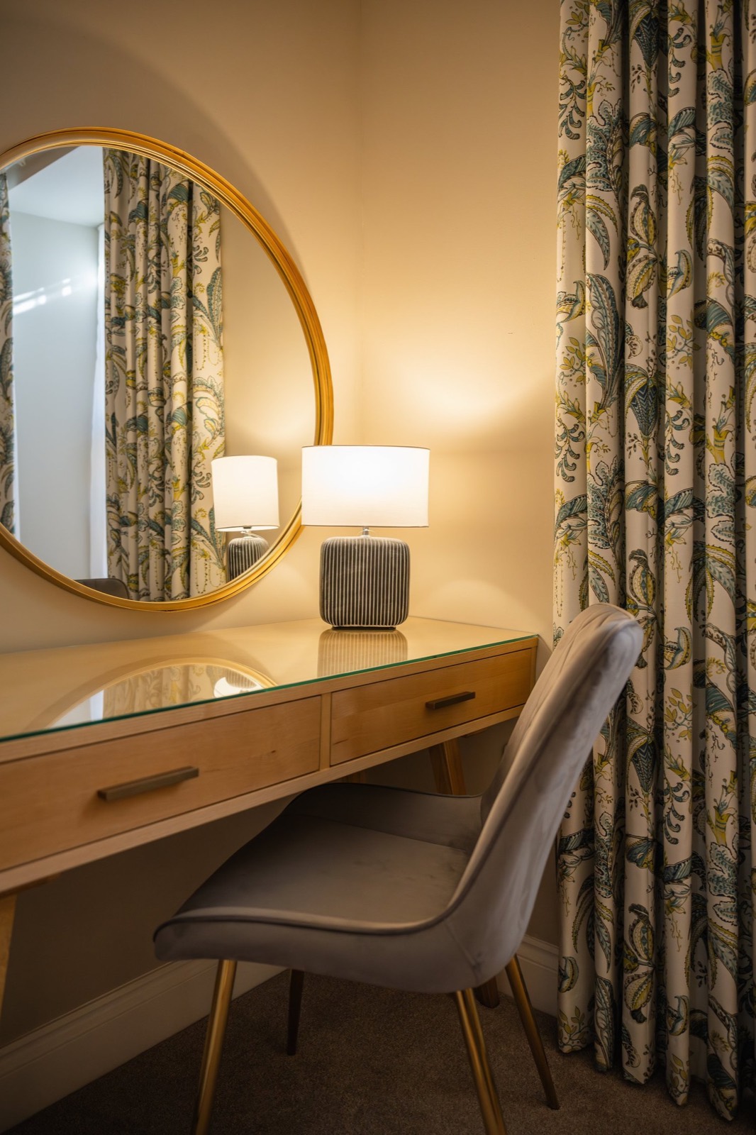 A dressing table with a round brass mirror