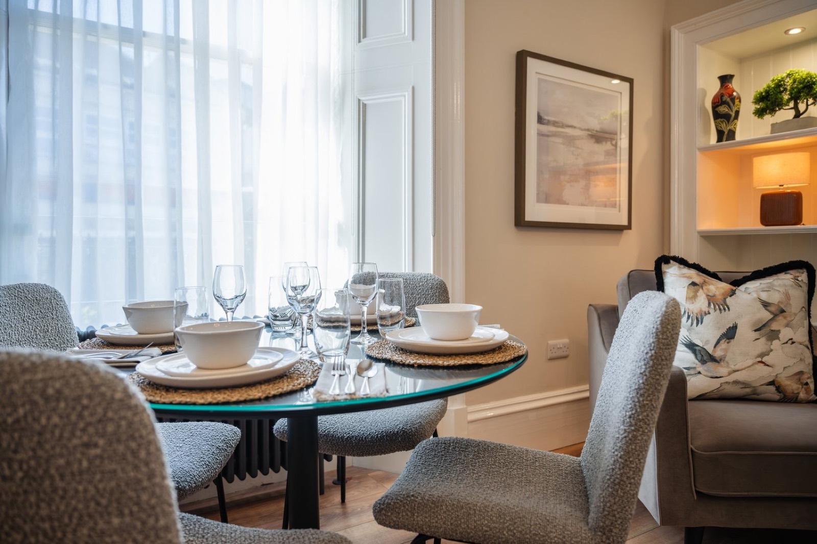 A dining table set by a bay window