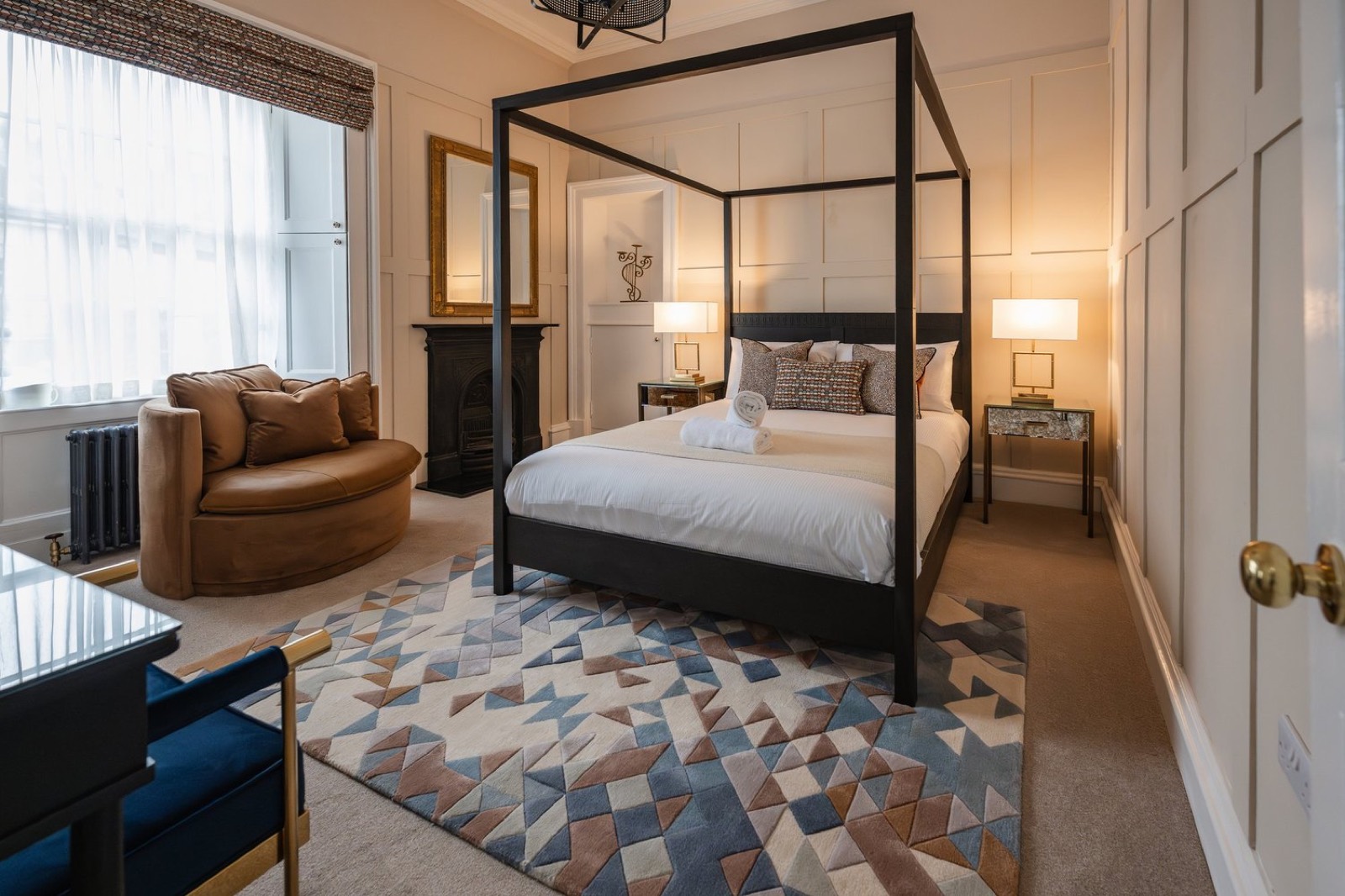 A bedroom with a four-poster bed and geometric rug