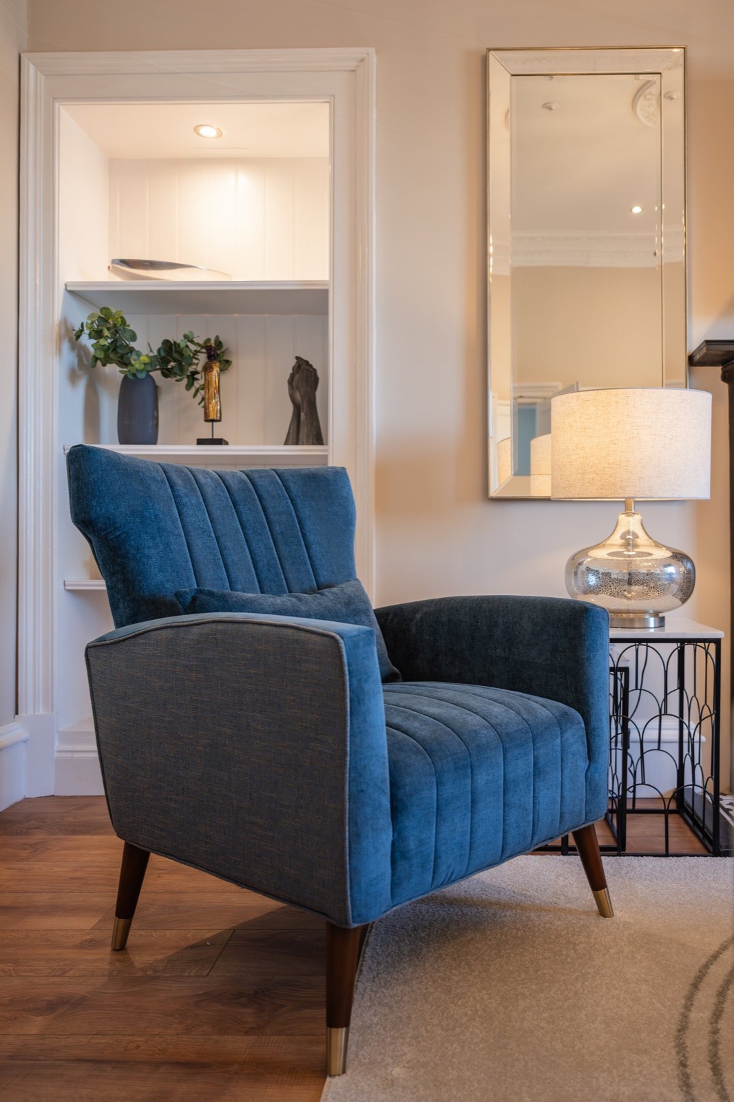 A blue velvet armchair beside an alcove