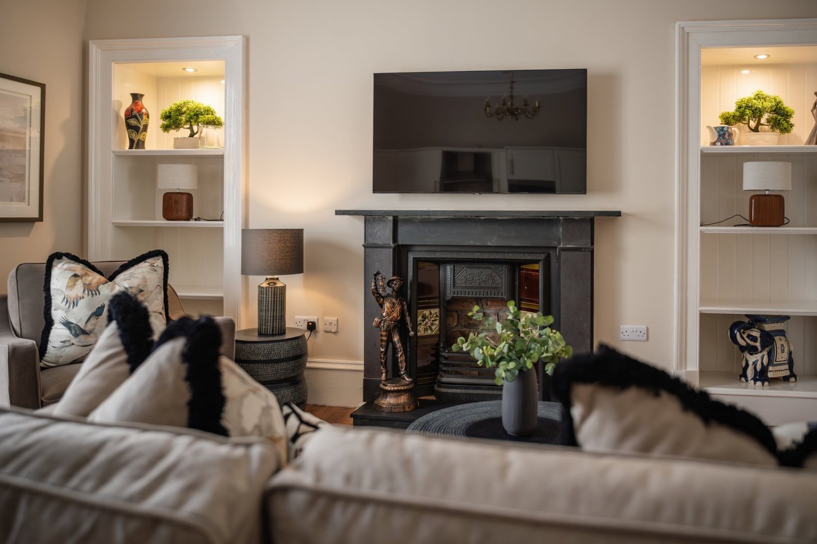 A sitting room with a fireplace and lit alcoves
