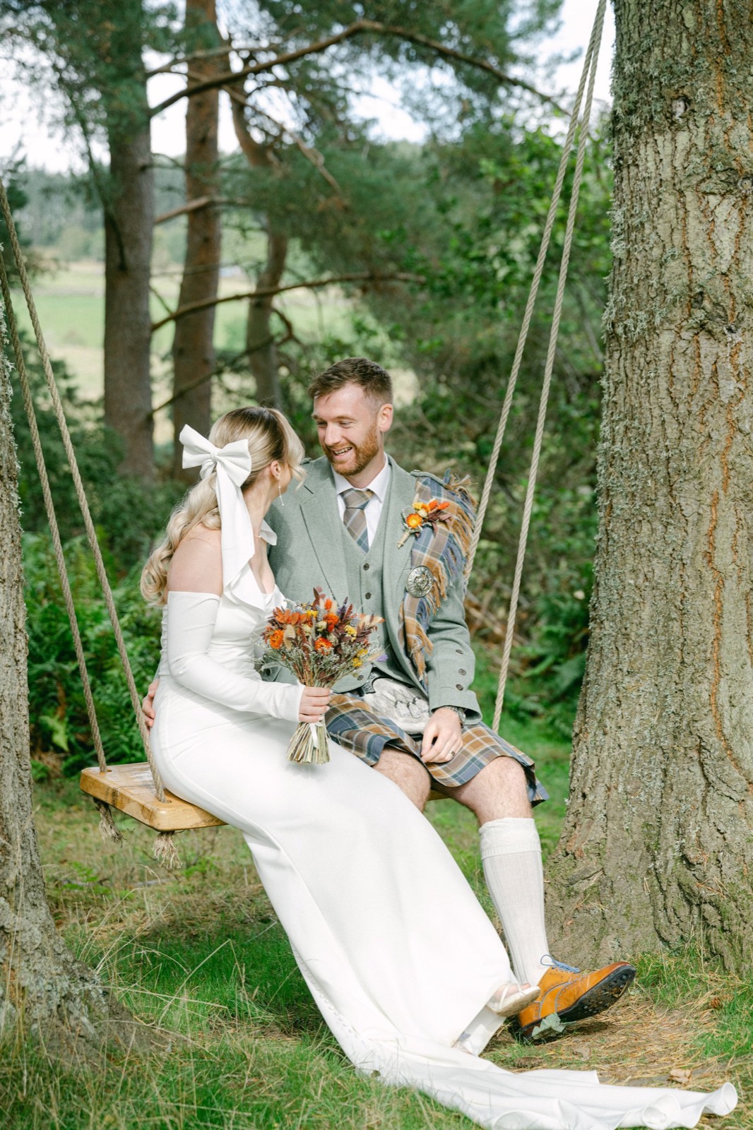 A bride and groom on a woodland swing