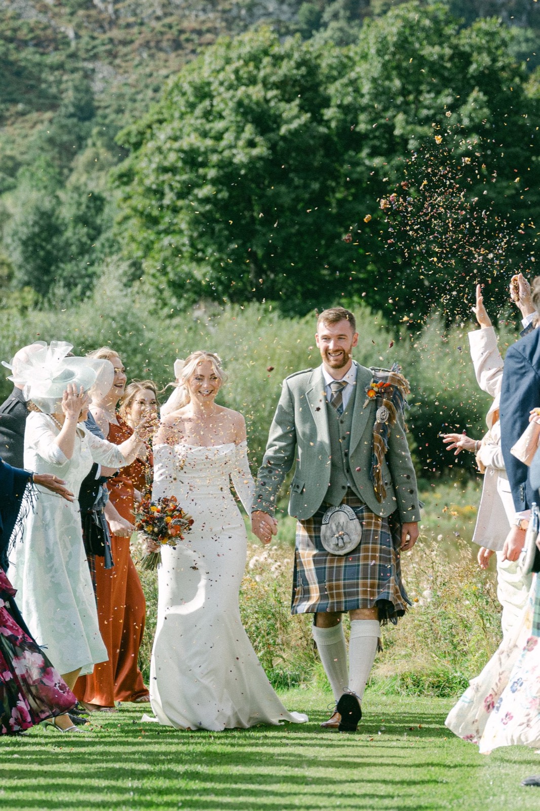 A bride and groom walking through a confetti shower