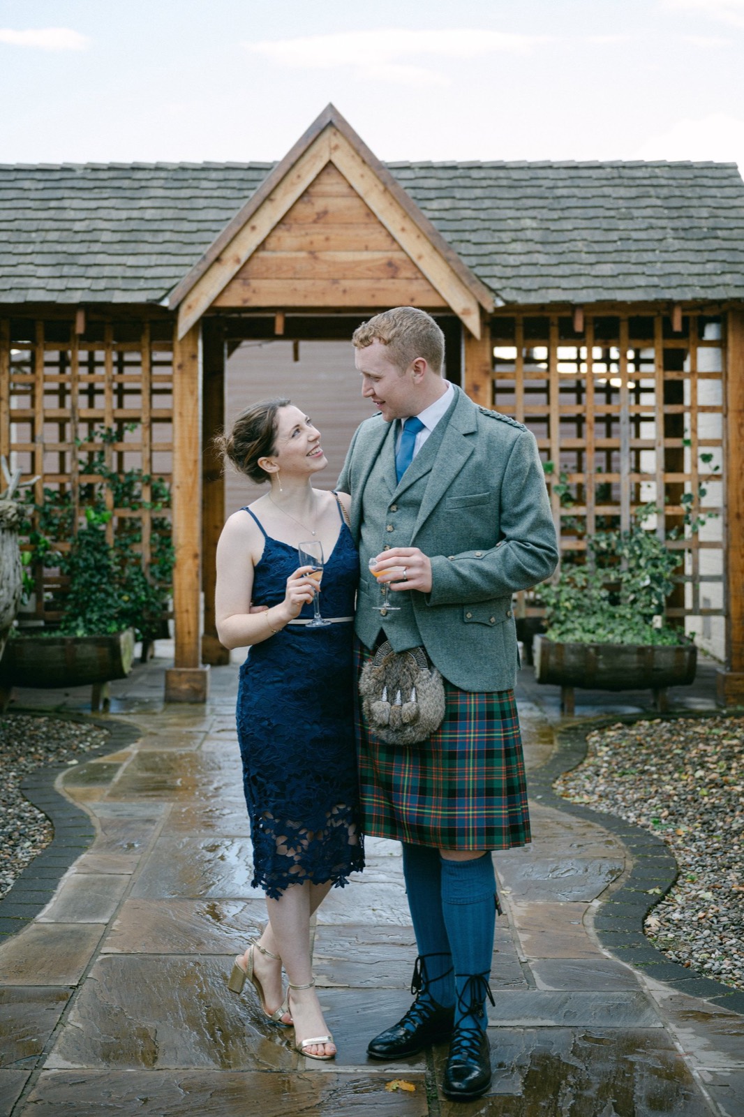 A couple in tartan beneath a wooden pergola