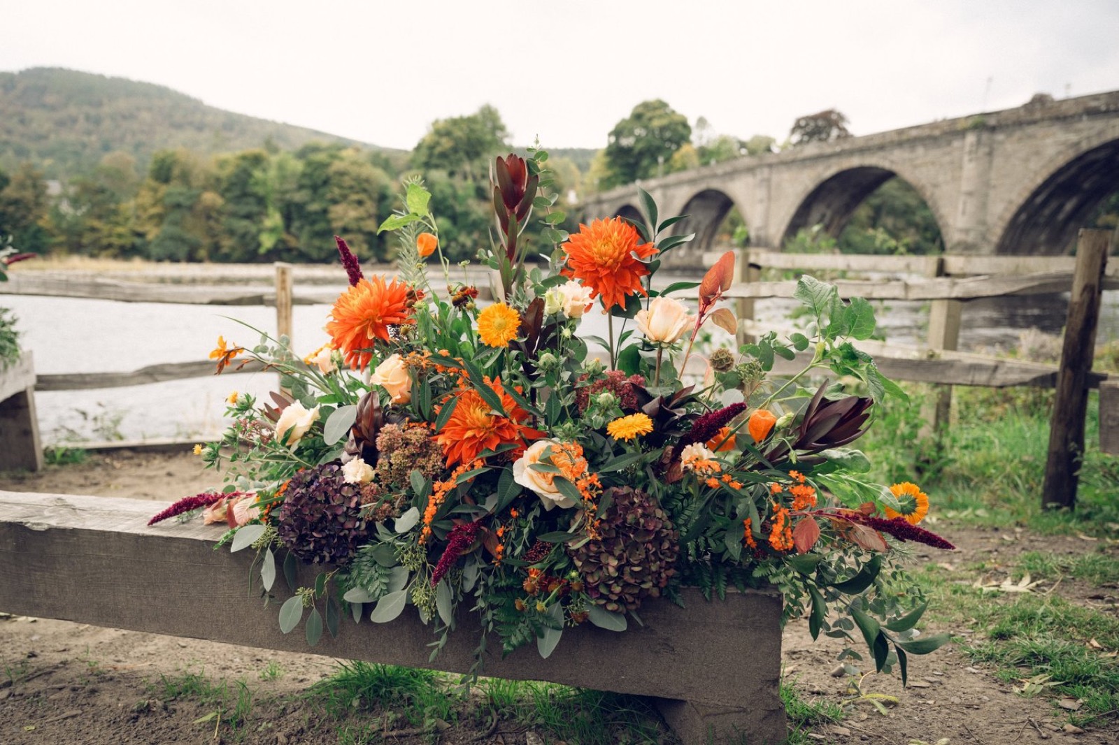 Wedding flowers on a bench by a stone bridge