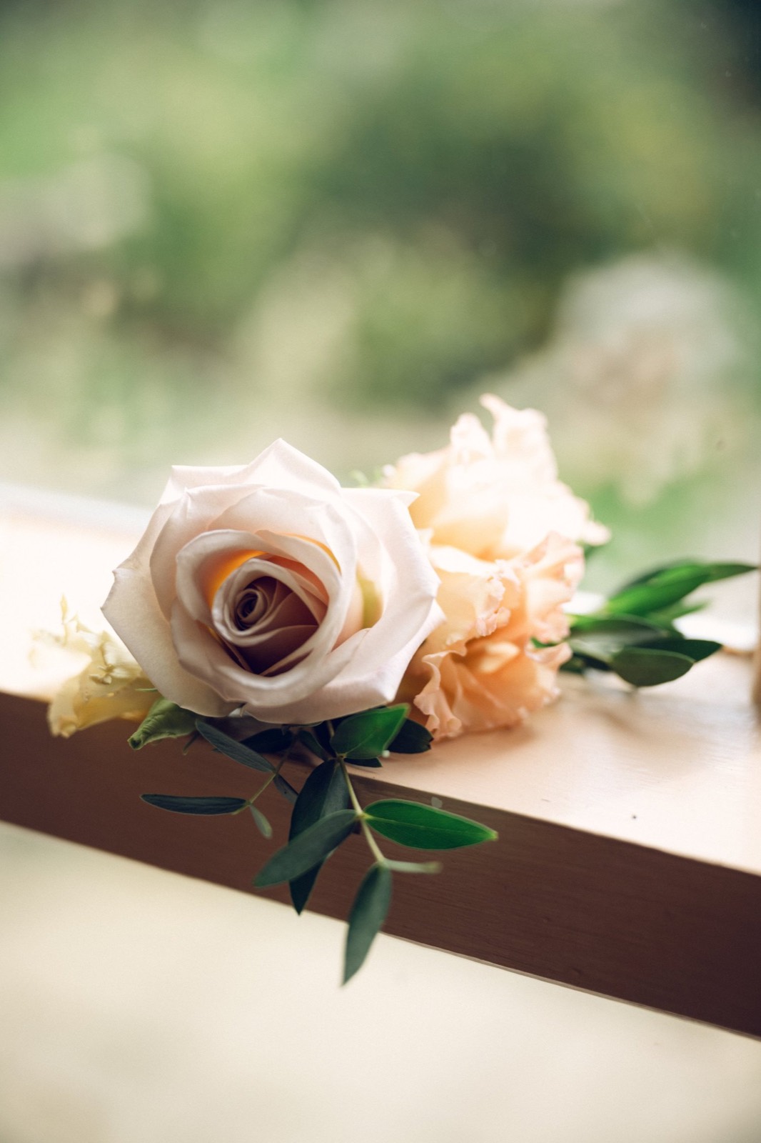 A rose buttonhole resting on a window ledge