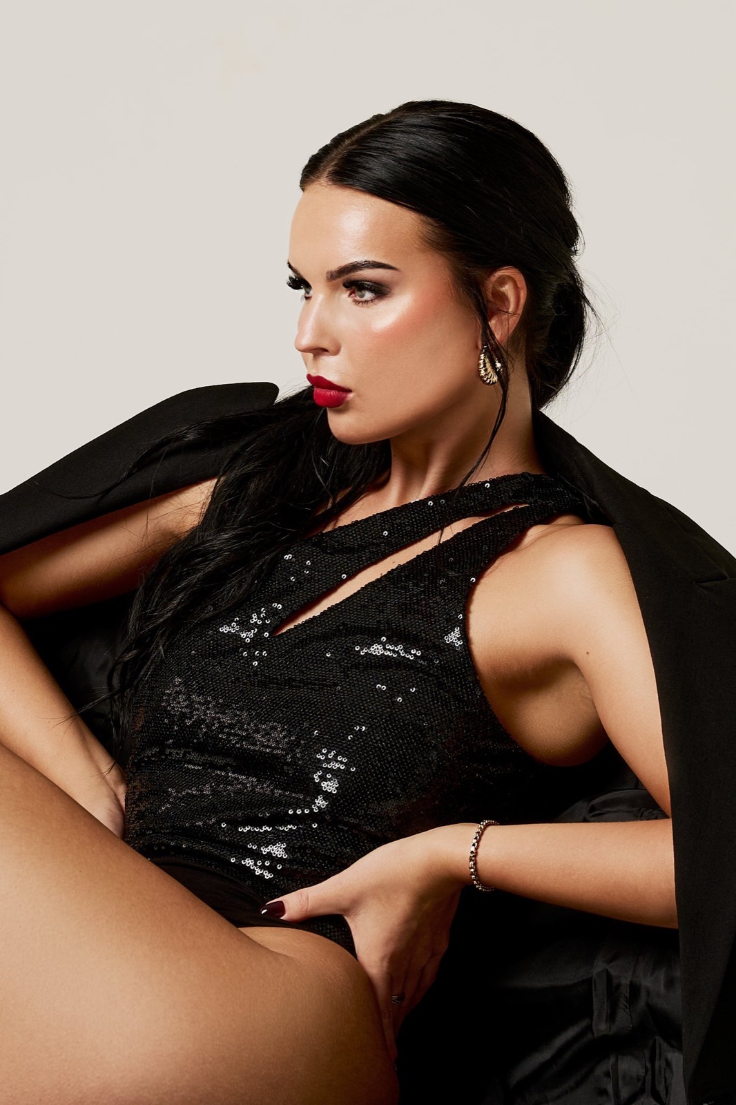 A woman in black sequins reclining, red lipstick