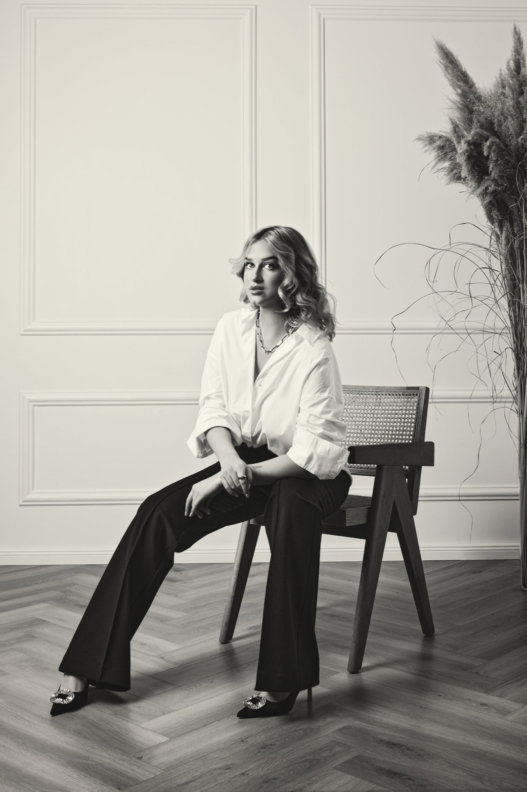 A black and white portrait of a woman seated in a panelled room