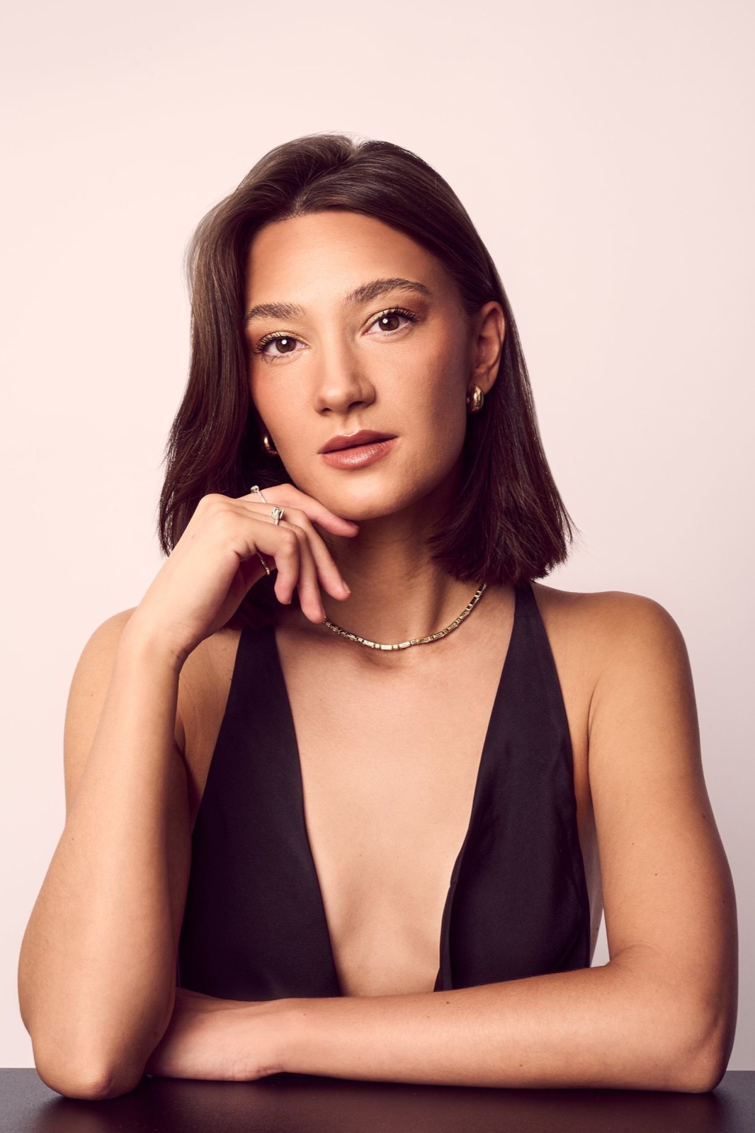 A woman in a black halterneck against blush