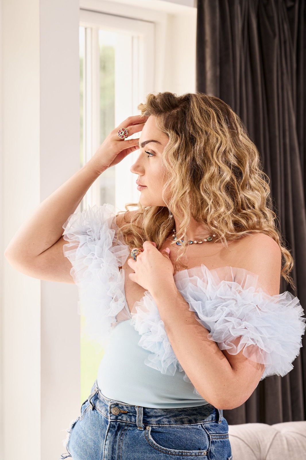 A woman in a tulle top by a bright window