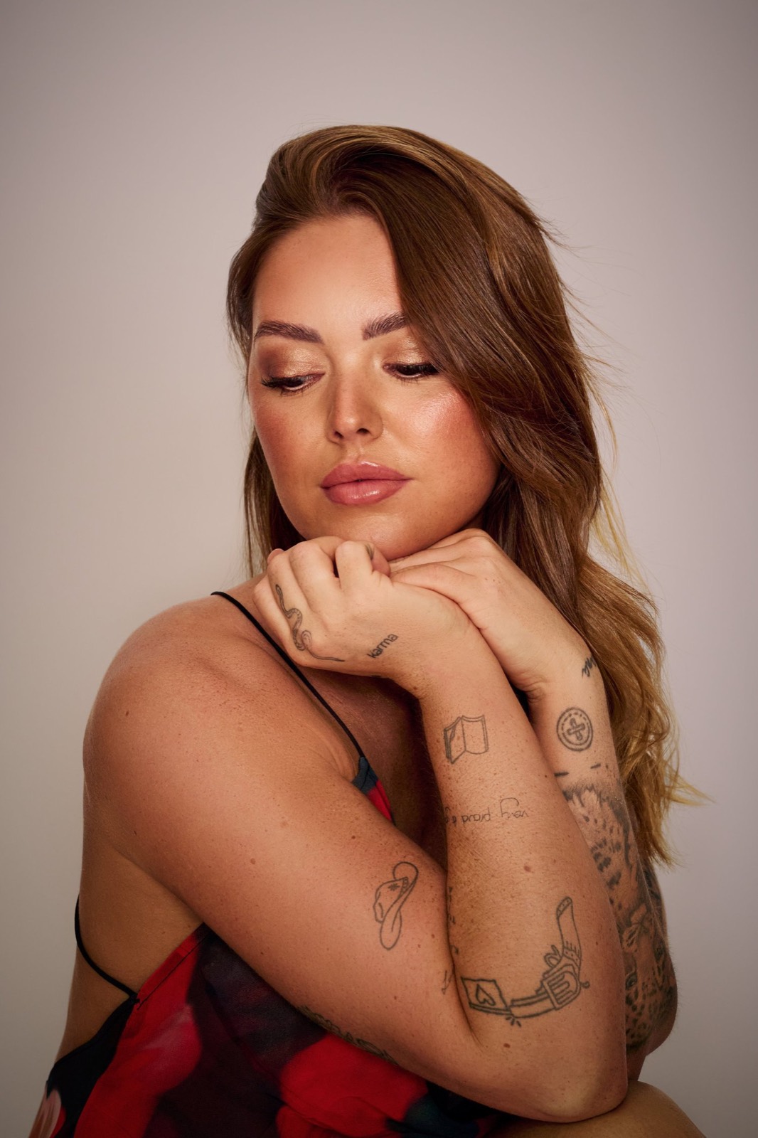 A woman with tattoos resting her chin on her hands