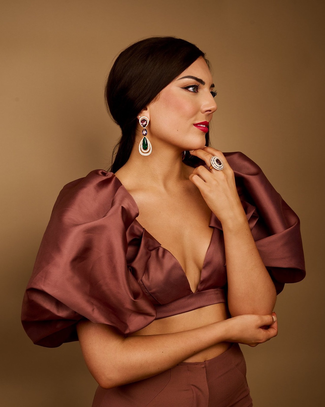 A woman in a burgundy satin top against brown