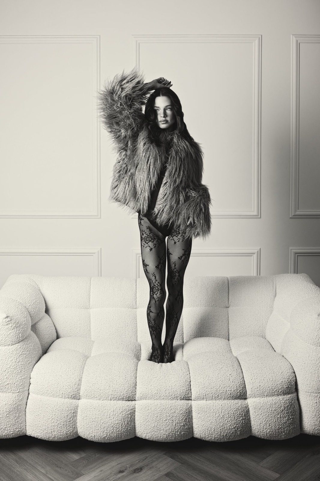 A black and white portrait of a woman in faux fur on a sofa