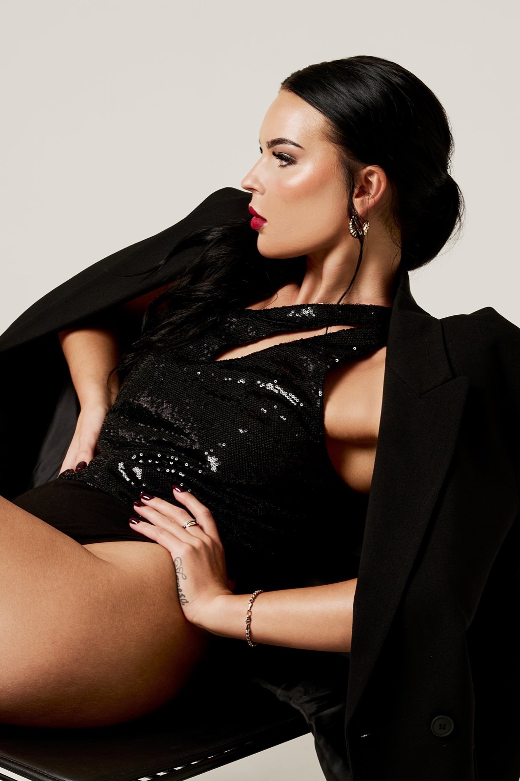 A woman in black sequins reclining on a chair