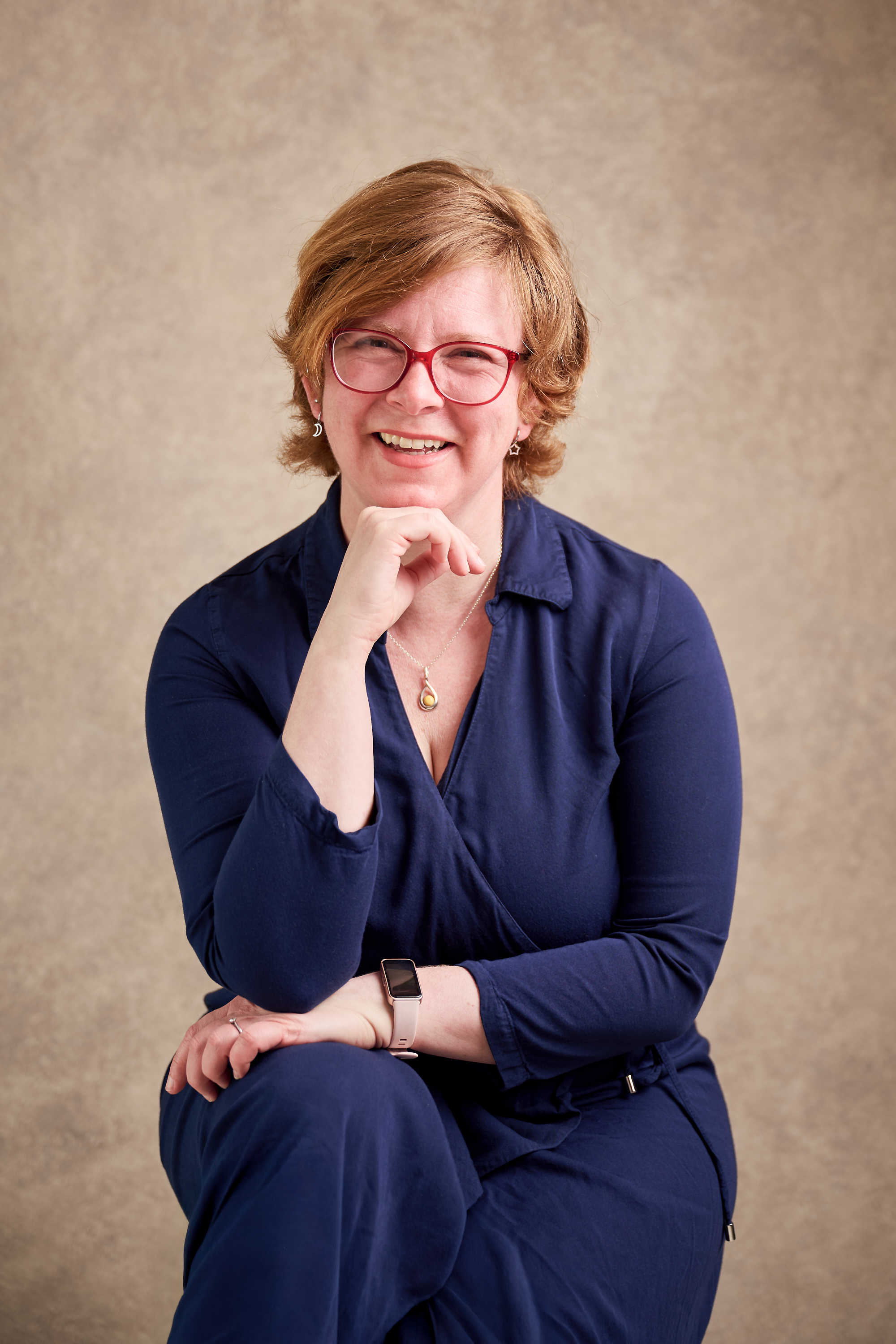 Sarah, photographed in a studio with a golden bespoke backdrop